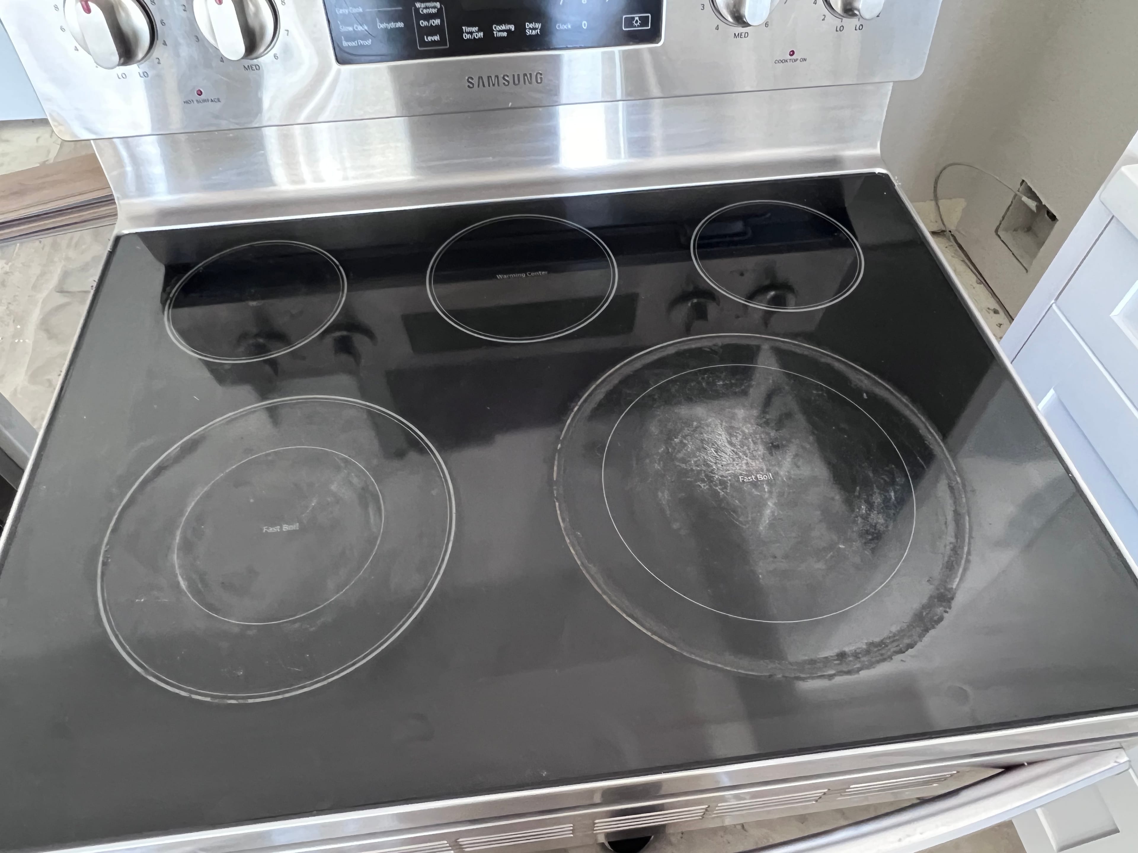 Dirty Samsung electric range with a black glass cooktop showing visible residue and stains on the burners.