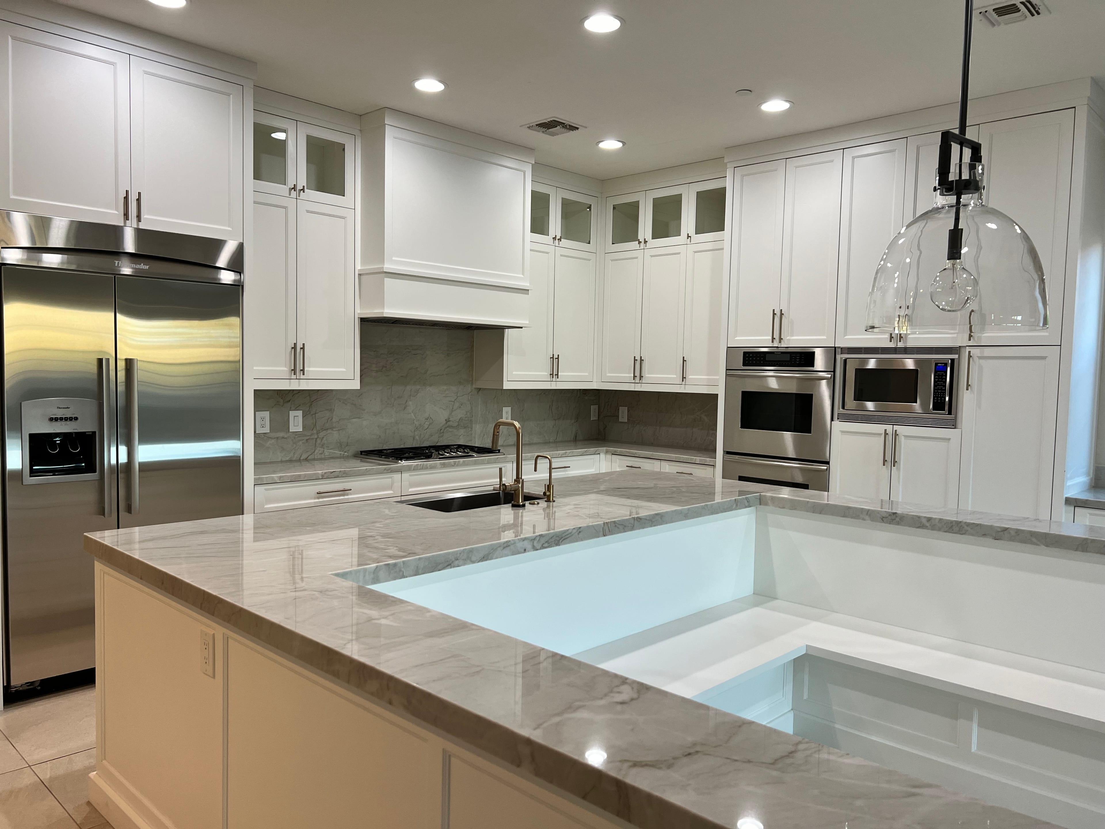 Open-concept living and dining room with new wood floors, white built-ins flanking a fireplace, and a kitchen island with cleaning supplies.